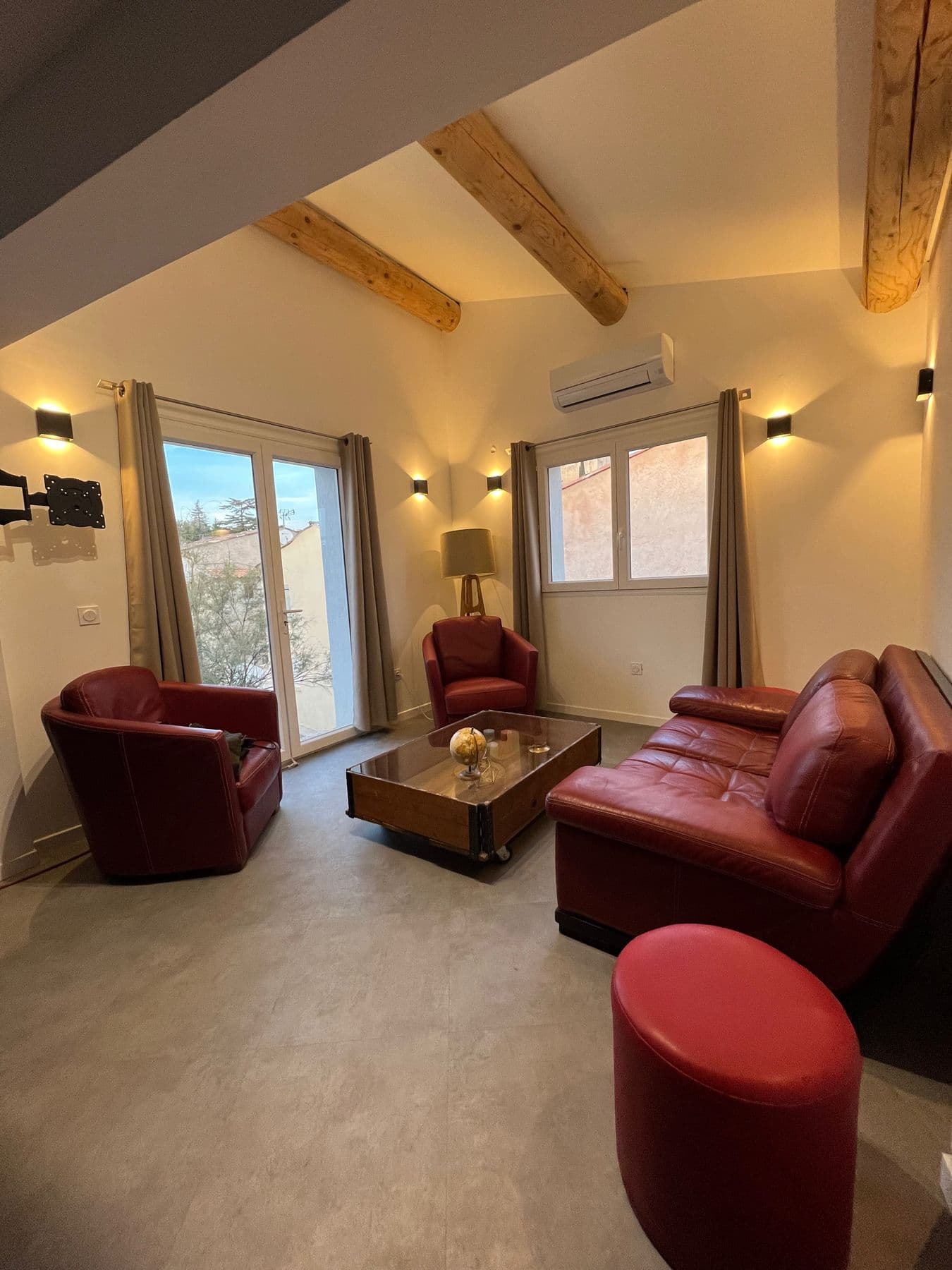 Le salon du T3 Terrasse, sous les poutres, avec ses fauteuils en cuir rouge